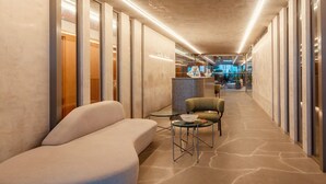 A modern hotel corridor with a sofa, a small table, and a chair. - Setai Yacht (João Pessoa)