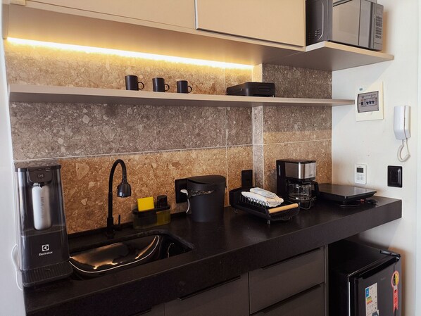 A modern kitchen with a built-in microwave, coffee maker, and kettle. - Setai Yacht (João Pessoa)