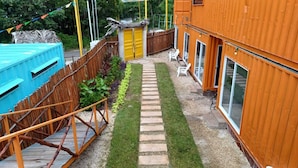 A backyard with a wooden deck, a small garden, and a yellow door. - Container Project  (Puerto Morelos)