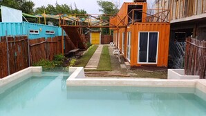 A swimming pool with a wooden deck and a small outdoor seating area. - Container Project  (Puerto Morelos)