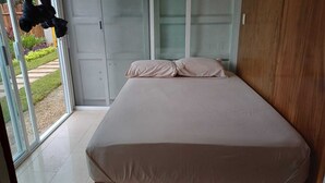 A bedroom with a bed, sliding glass doors, and a view of a garden. - Container Project  (Puerto Morelos)