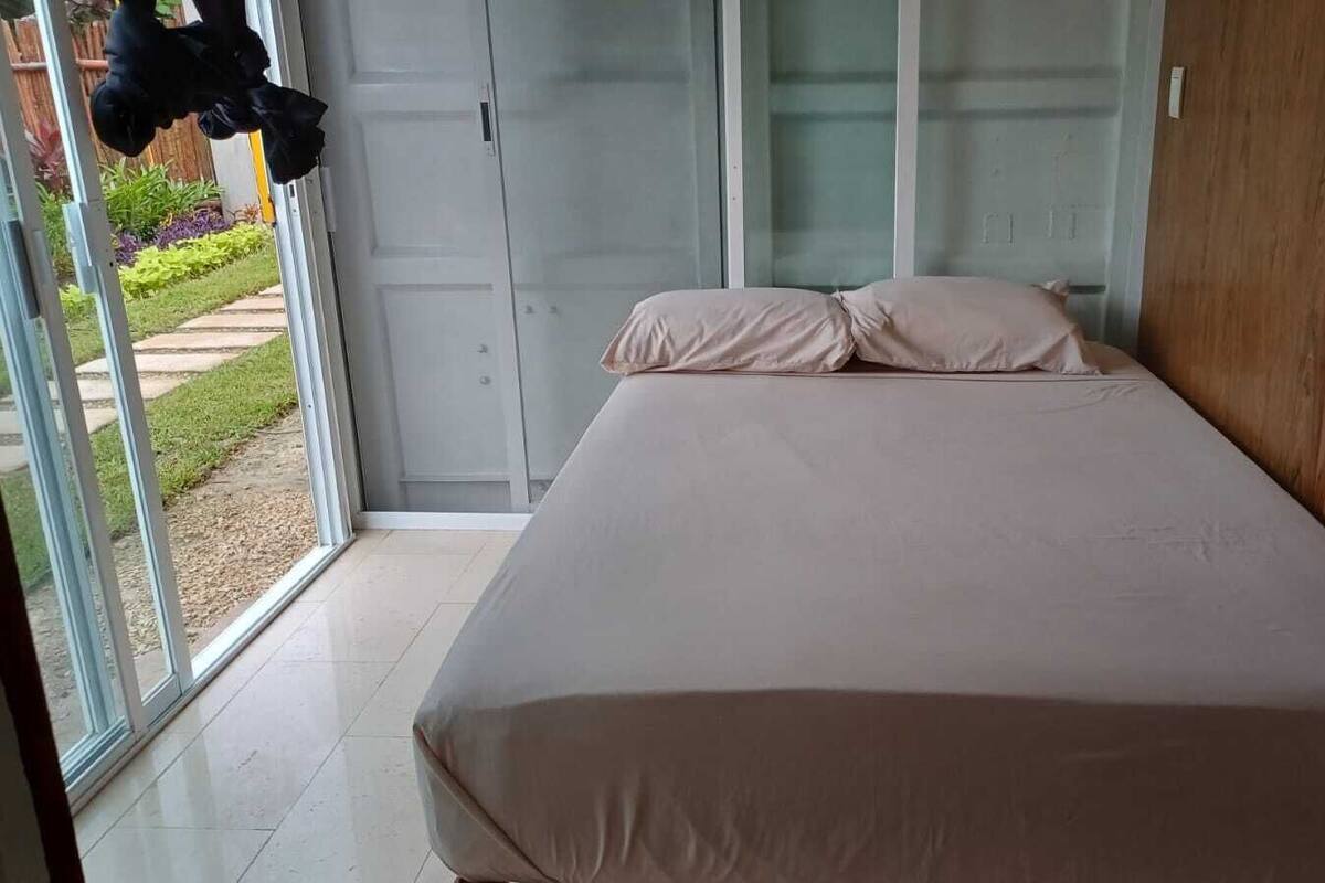 A bedroom with a bed, sliding glass doors, and a view of a garden.