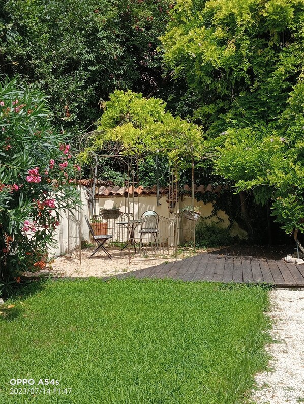 Ein Garten mit einer Terrasse, einem Metallzaun und einem Tisch mit Stühlen.