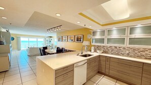 A modern kitchen with a central island, a dining area with a view, and a living space with a balcony.