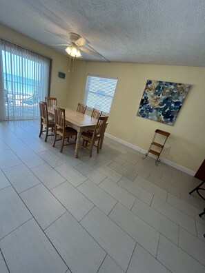 A dining area with a table and chairs, a ceiling fan, and a window with blinds.