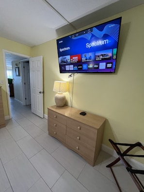 Habitación con un televisor de pantalla plana montado en la pared que muestra la interfaz de una plataforma de streaming.