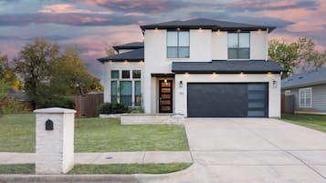 A modern two-story house with a garage, a stone mailbox, and a well-maintained lawn.