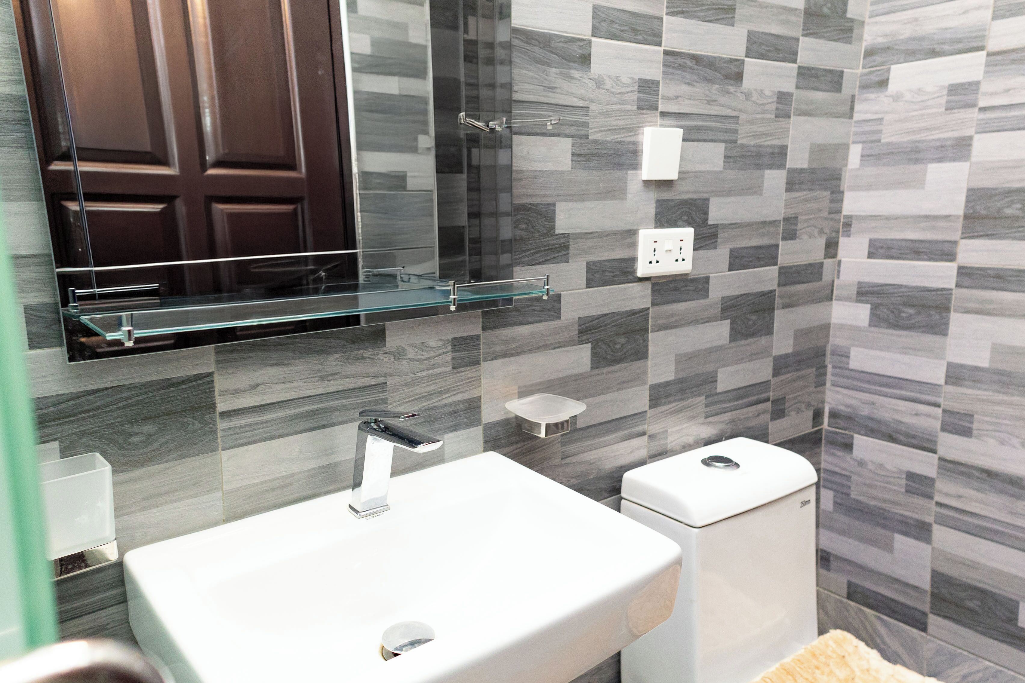 A modern bathroom with a glass shelf above the sink, a toilet, and a shower area.