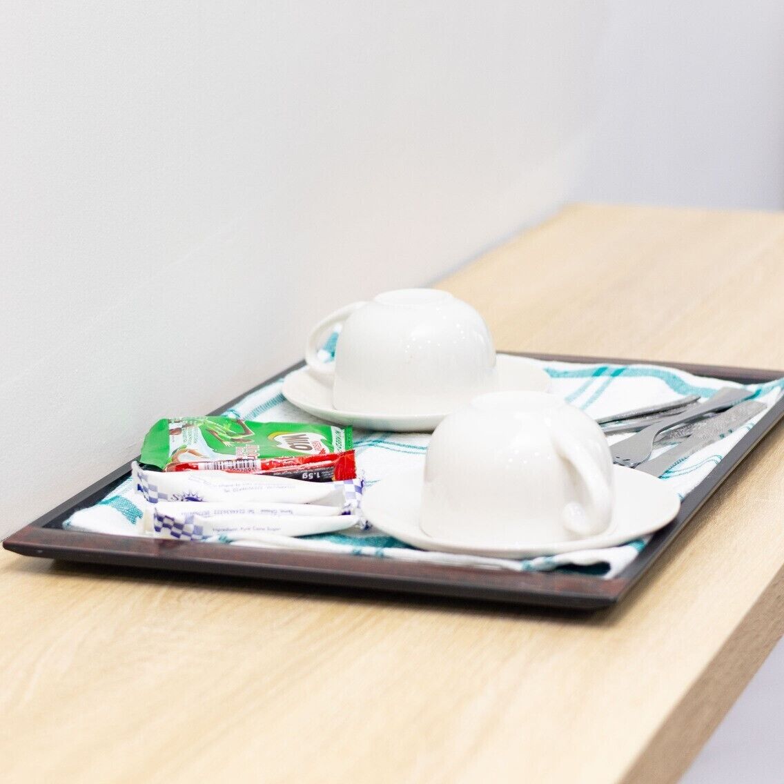 Ein Tablett mit Teekanne, Tasse und Teebeutel auf einer Holztisch.