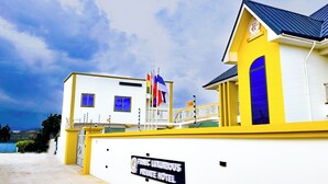 A private hotel with a yellow and white facade, a balcony, and a sign indicating it is a luxury hotel. - Firnic Luxurious Private Hotel (Kwabenya)