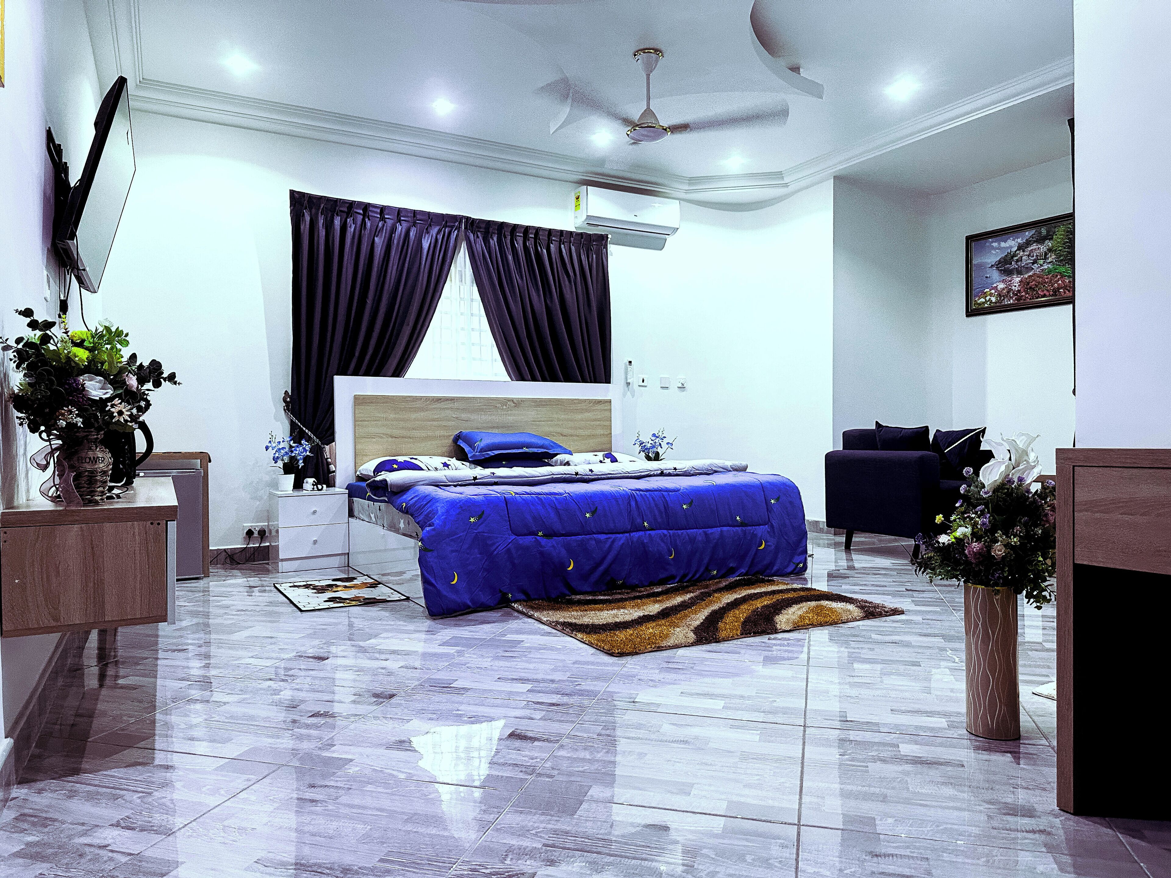 A modern bedroom with a large bed, a ceiling fan, and a view of the city.