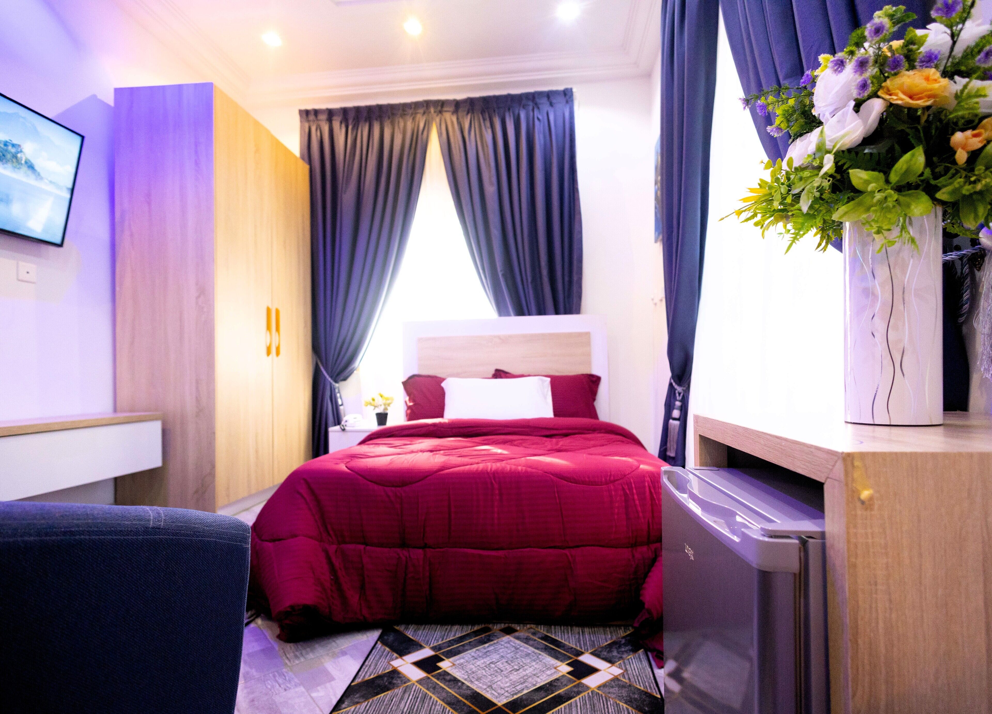 A modern hotel room with a large bed, a desk, and a TV mounted on the wall.