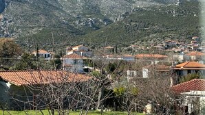 Un paysage montagneux avec un village au premier plan, caractérisé par des bâtiments traditionnels aux toits recouverts de tuiles rouges.