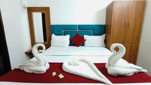 Una habitació d'hotel amb un llit, un armari de fusta i dues tovalloles amb forma de cigne damunt el llit.