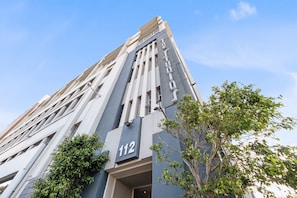 A modern building with a prominent number '112' on its facade, large windows, and a tree in the foreground. - The Studios 309 - One Bedroom Apartment, Sleeps 2 (Cape Town)