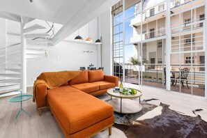 A modern living room with a sectional sofa, a coffee table, and a glass table. - The Studios 309 - One Bedroom Apartment, Sleeps 2 (Cape Town)