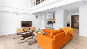 Un salon moderne avec un canapé, un téléviseur et un coin repas à l’arrière-plan.