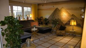 A living room with a large potted plant, a sofa, a coffee table, and a lamp.