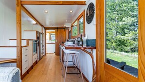 A compact kitchen with wooden cabinetry, a bar area, and a view of the outdoors.