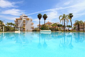 A swimming pool with a reflection of a building and palm trees. - CT 108 - Calanova (Mijas)