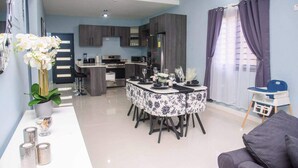Una cocina moderna con armarios oscuros, un comedor con mesa redonda y una sala de estar con sofá.