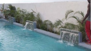 Piscina con cascada y follaje circundante.
