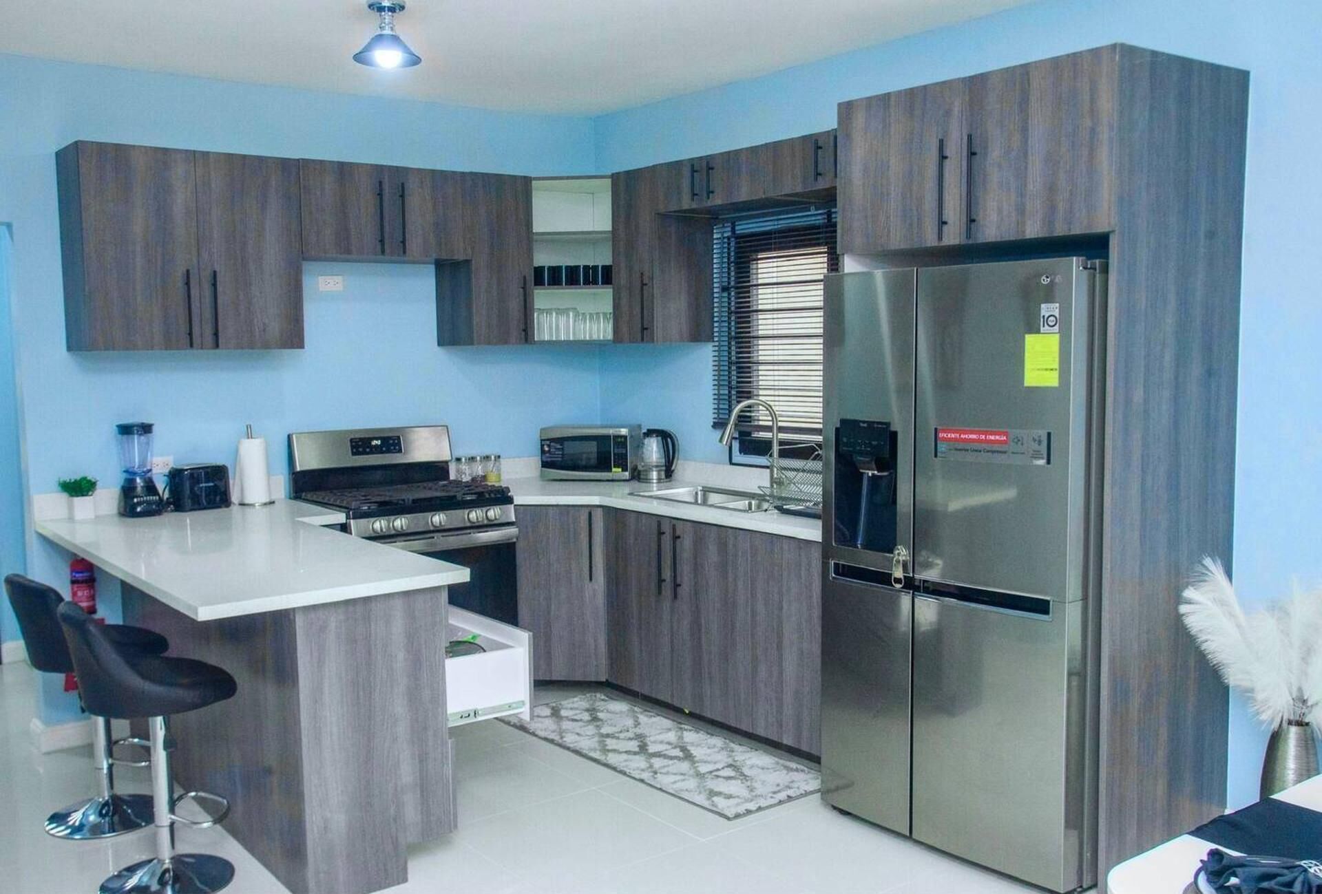 Una cocina moderna con armarios de madera, un refrigerador de acero inoxidable, un microondas, una estufa y un lavamanos.