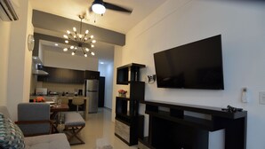 A modern living room with a flat-screen TV, a fireplace, and a dining area with a kitchen in the background. - CasMar - 2 (Puerto Vallarta)