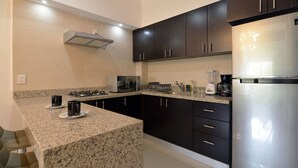 A modern kitchen with dark cabinets, granite countertops, and stainless steel appliances including a refrigerator, microwave, and coffee maker. - CasMar - 2 (Puerto Vallarta)