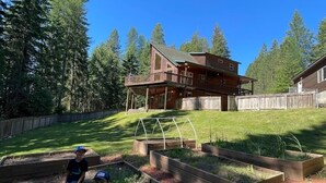 A house with a large deck and a well-maintained garden with raised beds. - Charming Secluded  3-bedroom house in Sagle ID close to Lake and Schweitzer Ski (Sagle)