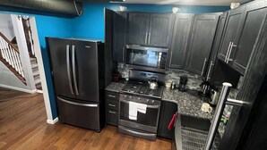 A modern kitchen with dark cabinets, stainless steel appliances, and a granite countertop.