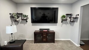 A modern living room with a flat-screen TV, dark wood entertainment center, and a magazine on the coffee table.