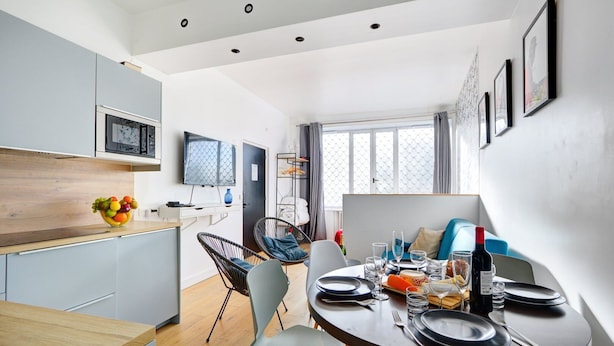 A modern kitchen with a dining area, wooden cabinets, a fruit bowl, and a dining table set for four.