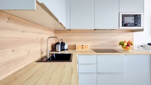 A modern kitchen with a wooden countertop, a black sink, a microwave, and a fruit bowl.