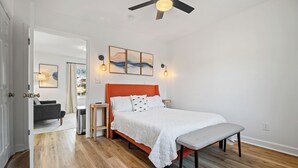 Un dormitorio con cama, banca y una obra de arte en la pared.