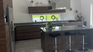 A modern kitchen with a central island, bar stools, and a built-in oven.