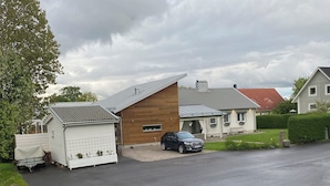 A residential street with houses, a parked car, and a trailer.