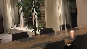 A dining area with a wooden table, six chairs, and a potted plant.