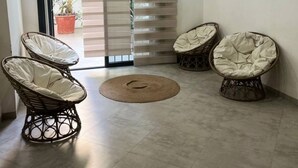 A modern room with two wicker chairs, a round woven rug, and a sliding glass door leading to a balcony with plants. - Cosy F3 in the center of Dakar (Dakar)