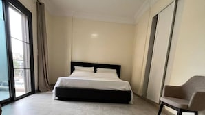 A modern hotel room with a large bed, a chair, and a view through the window. - Cosy F3 in the center of Dakar (Dakar)