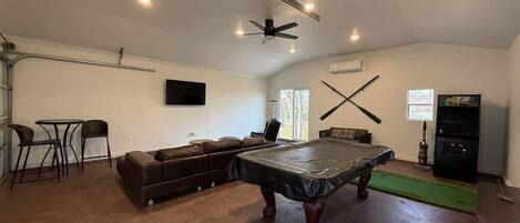 {GAME ROOM} The garage has been transformed into the ultimate game room, featuring a pool table, arcade machine, 70" smart TV, fishing poles, mini putt and a spacious couch. It's the perfect hangout spot for fun and relaxation!