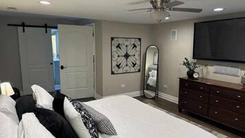 {MASTER BEDROOM} Refresh in the master bedroom with a plush king bed, 65" smart TV, dresser, and closet. The ensuite bathroom features a relaxing soaking tub and a stand-up shower for ultimate comfort.
