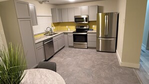 Una cocina moderna con gabinetes grises, electrodomésticos de acero inoxidable, microondas, horno y refrigerador.
