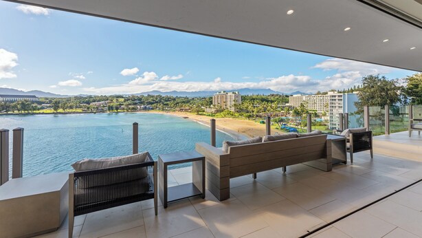 Un espace extérieur moderne, aménagé pour se détendre, avec vue sur une plage et des montagnes.