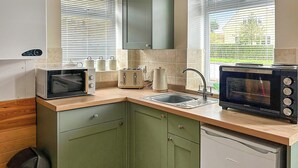 Een kleine keuken met een magnetron, broodrooster, spoelbak en vaatwasser.