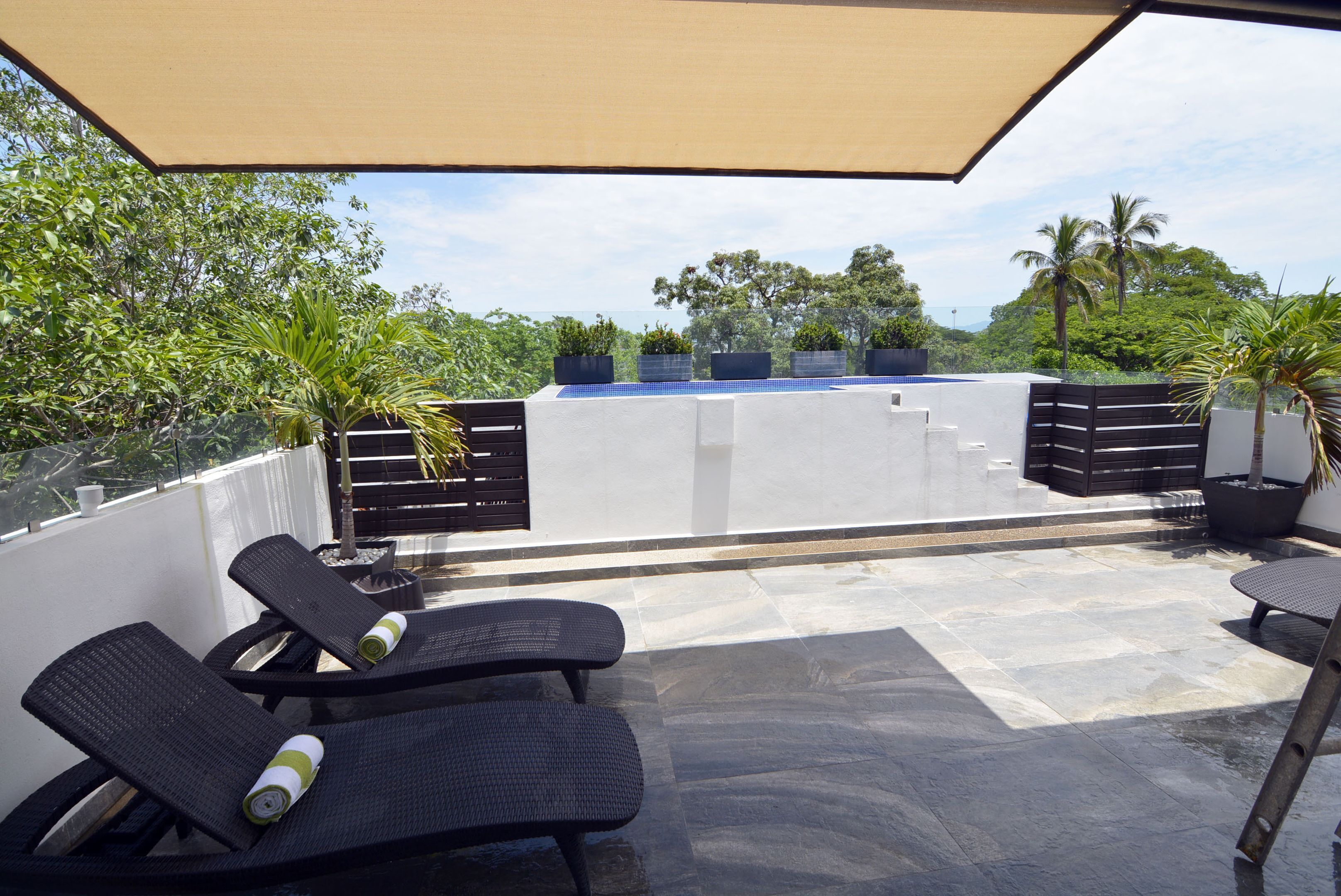 Eine Dachterrasse mit Liegestühlen, einer Pergola und Topfpflanzen.