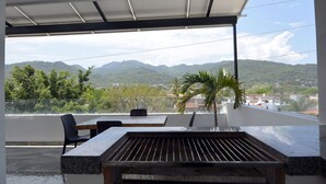 Un balcon avec vue sur les montagnes, un barbecue et des meubles pour se détendre en plein air.