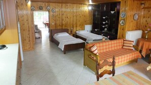 A wooden-furnished room with two beds, a sofa, and a dining table.