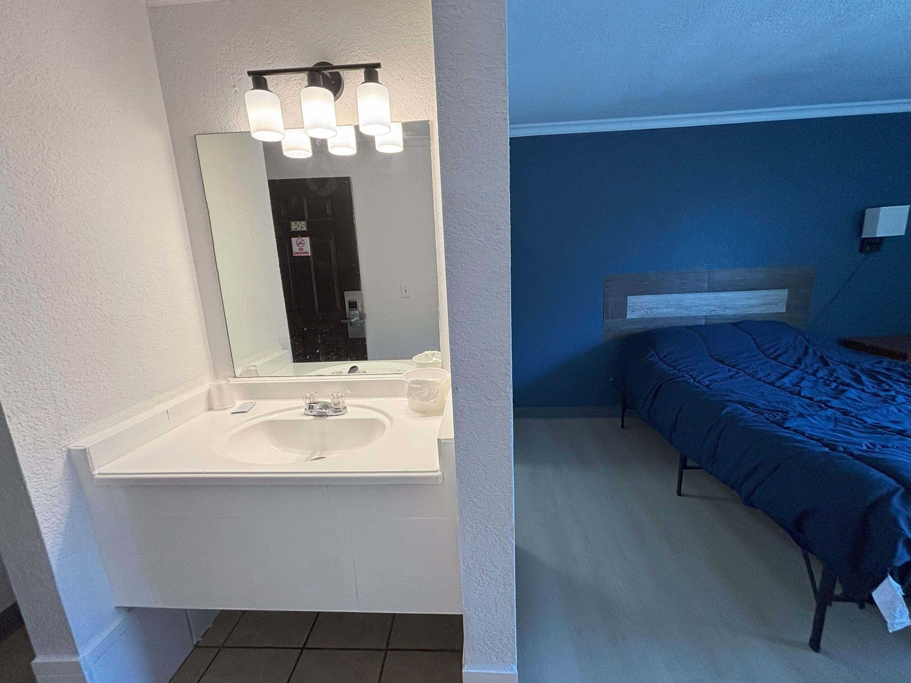 Un baño con lavamanos blanco, espejo y tres lámparas sobre él.