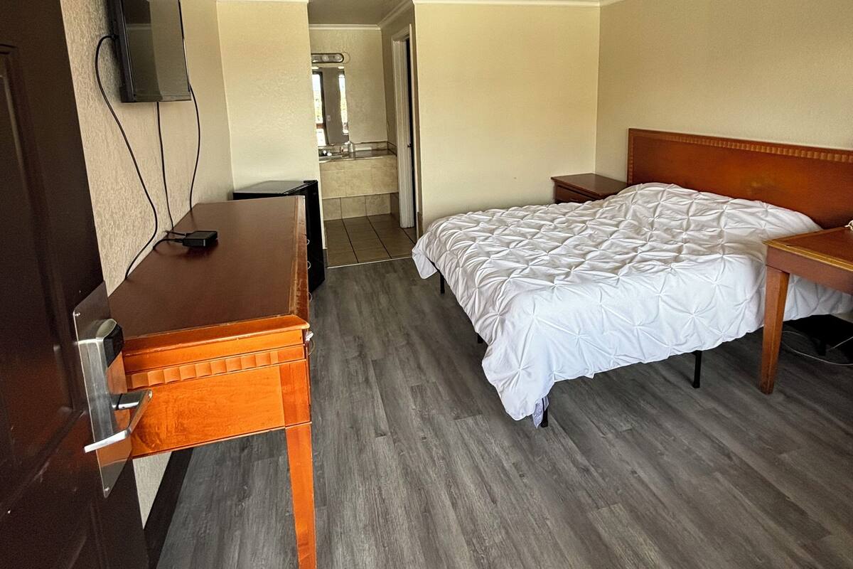 A hotel room with a bed, a desk, and a television mounted on the wall.